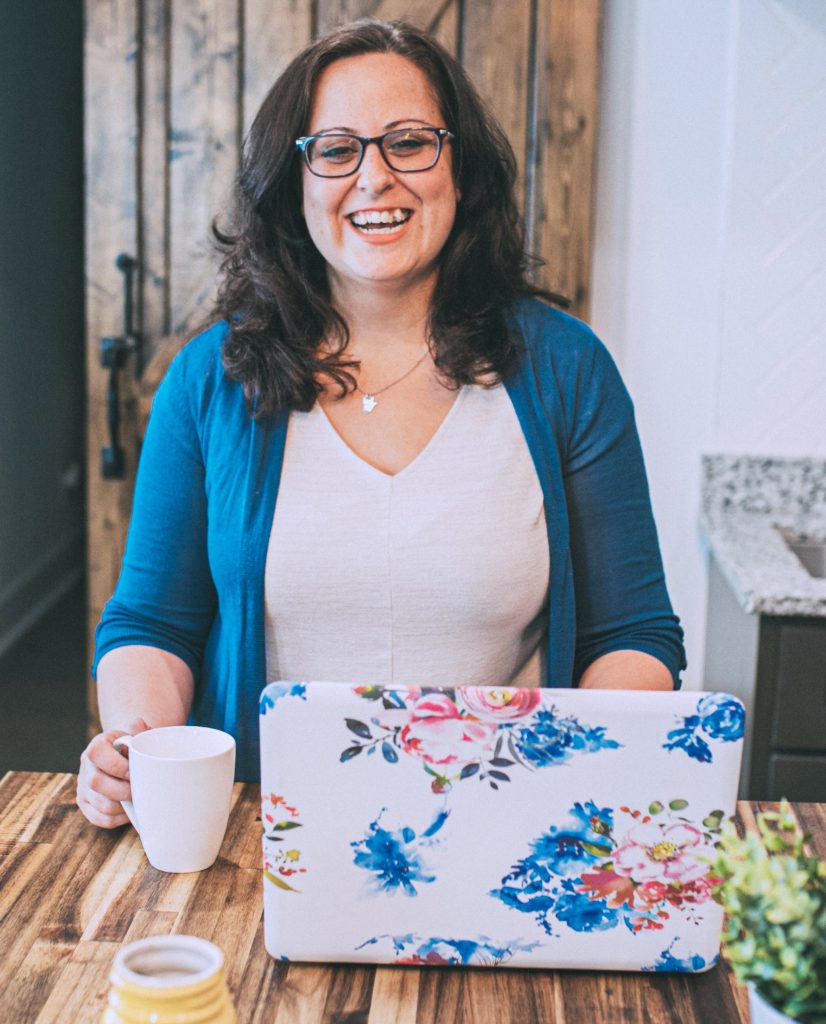 Chrissy Beltran stands behind an open laptop.